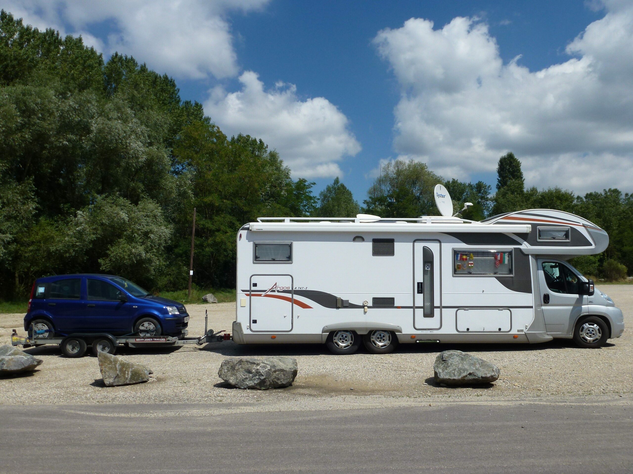 Camping-car à double essieu tractant une remorque à voiture