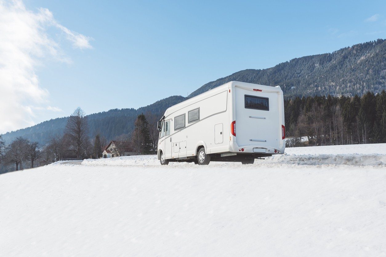Un camping-car sur une route enneigée.